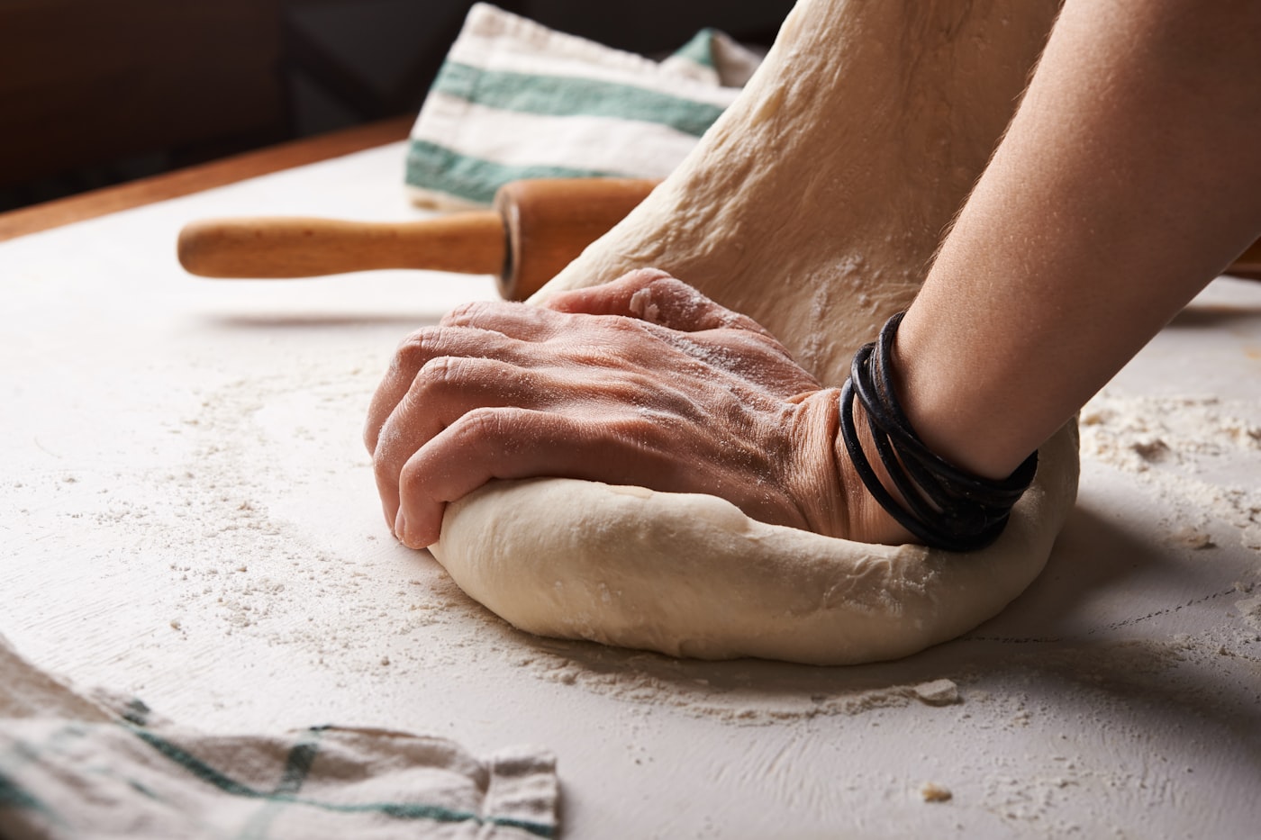 Hands kneading fresh dough on a floured table